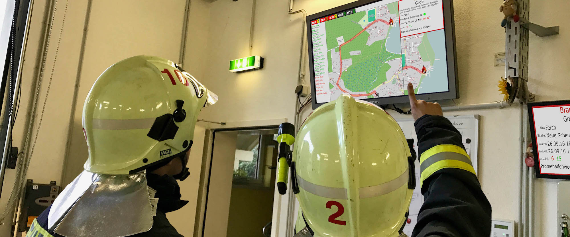 Feuerwehrkräfte vor einem SANDRA Einsatz-Display